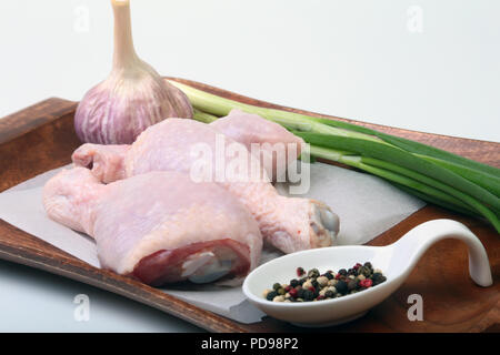 Cuisses de poulet cru avec des épices, ail et oignon vert sur une planche de bois. Prêt pour la cuisson. Banque D'Images