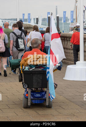 Un homme monté sur un scooter pour personnes handicapées sur le front de mer à Cowes sur l'île de Wight au cours de la semaine de Cowes. homme handicapé en scooter ou handicap transport. Banque D'Images