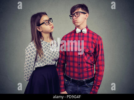 Jeune homme et femme en couple expression de désaccord et d'infraction tout en regardant l'un l'autre sur fond gris Banque D'Images