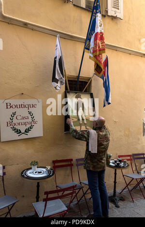 Un barman en joignant une copie du portrait peint de Napoléon Bonaparte sous le drapeau national Corse et la bataille de Napoléon à l'extérieur du pavillon Solebone Casa Banque D'Images