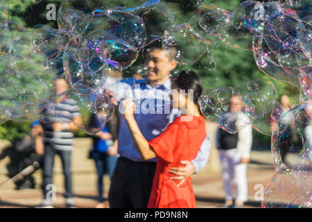 New York, États-Unis - 24 septembre 2016. Couple jouant avec des bulles de savon arc-en-ciel géant flottant dans l'air d'été au cours d'une belle journée ensoleillée Banque D'Images