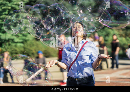 New York, États-Unis - 24 septembre 2016. Jeune femme jouant avec des bulles de savon arc-en-ciel géant flottant dans l'air d'été Banque D'Images