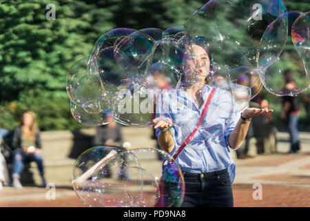 New York, États-Unis - 24 septembre 2016. Jeune femme jouant avec des bulles de savon arc-en-ciel géant flottant dans l'air d'été Banque D'Images