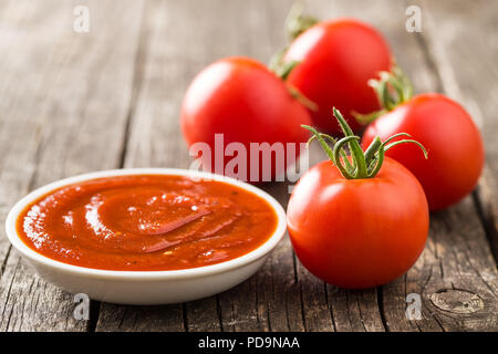 La tomate et le ketchup sur la vieille table en bois. Banque D'Images