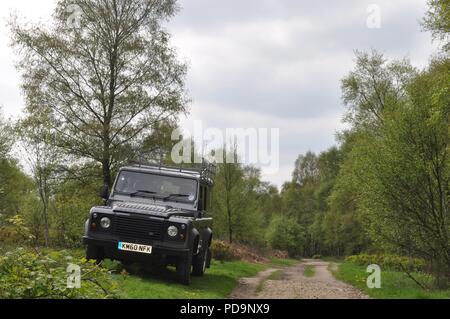 Black Land Rover Defender sans rouler sur un chemin à travers les bois après être allé tout-terrain (off road) Land Rover Banque D'Images