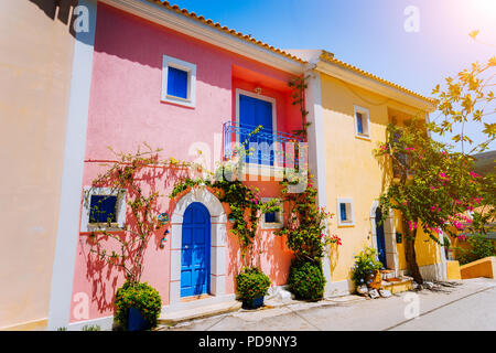 Village d'Assos. Maisons traditionnelles grecques de couleur bleu clair avec des portes et fenêtres. La floraison des fleurs autour de l'usine fucsia entrée bienvenue portes. L'île de Céphalonie, Grèce Banque D'Images