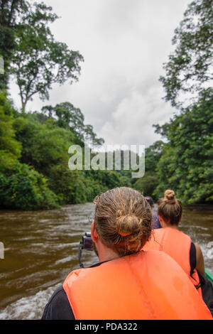 Les touristes de l'Ouest dans des vestes de prendre des photos et profiter de leurs visites en bateau sur une rivière avaler par de fortes pluies le long d'une rivière Banque D'Images