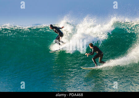 Surfer en baisse dans sur un autre surfeur sur une vague à droite Banque D'Images