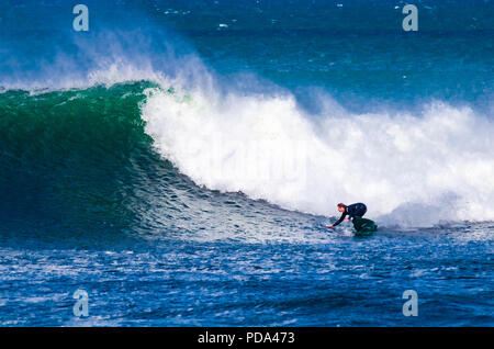 L'exécution d'un surfeur bottom turn sur une grande vague de Bells Beach, Great Ocean Road, Victoria, Australie Banque D'Images