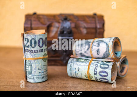 Roulé et empilés 20000 billets forint avec une boîte en bois vintage fermée à l'arrière-plan Banque D'Images