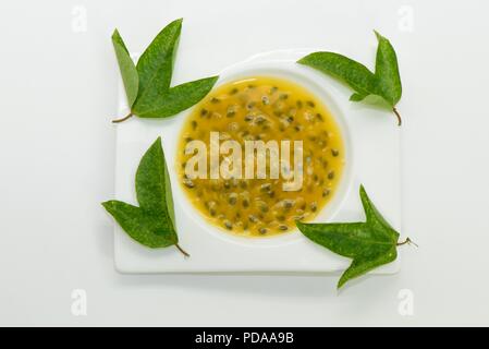 Jus de fruits de la passion avec des feuilles vertes on white plate Banque D'Images