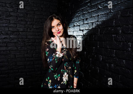 Portrait d'une jeune femme en robe à fleurs dans le noir studio. Banque D'Images