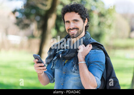 Portrait d'un homme à l'aide de son téléphone mobile dans un parc Banque D'Images