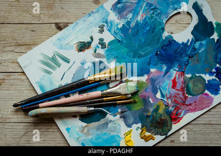 Les pinceaux de l'artiste sur palette en bois. Les peintures à l'huile mélangée de texture en différentes couleurs. Les instruments et les outils pour les loisirs créatifs. Hobby peinture backg Banque D'Images