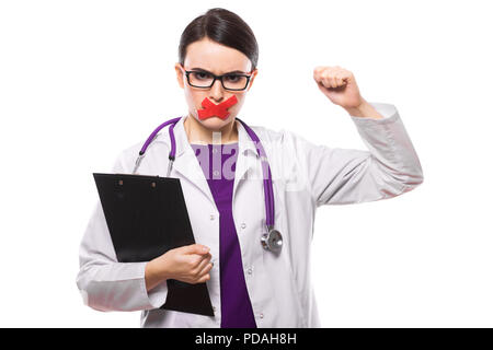 Young woman doctor with stethoscope holding clipboard dans ses mains avec du ruban adhésif à lèvres uniforme blanc sur fond blanc Banque D'Images