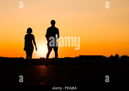 Silhouette d'girl boy sur fond de ciel coucher de soleil Banque D'Images