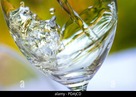 Verser le verre de vin blanc close up capture splash action tourbillonnant en situation d'été en plein air table de jardin Banque D'Images