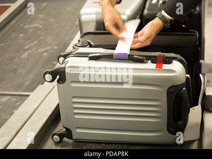 Check-in employé attache une étiquette à bagages valise de passagers dans l'aéroport. Banque D'Images