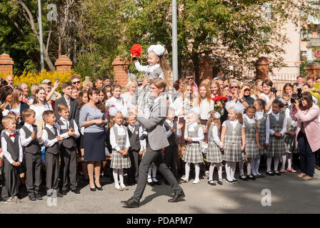 Tioumen, Russie - septembre 1, 2017 : gymnase numéro 5. Garçon plus âgé, adolescent, de race blanche, porte petit écolière avec la cloche. Première sonnerie à new scho Banque D'Images