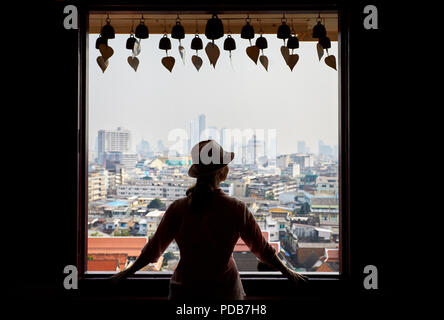 Silhouette d'femme à la fenêtre de vue sur la ville de Bangkok de gratte-ciel du quartier des affaires à partir de la montagne d'or à la Pagode Wat Saket couvert Banque D'Images