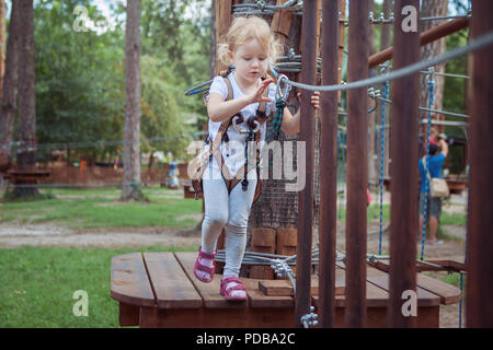 Petite fille dans l'équipement permet de surmonter l'obstacle dans le parc. Banque D'Images