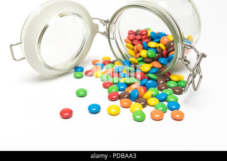 Smarties colorés de renverser un pot de rangement alimentaire verre couché sur le côté Banque D'Images
