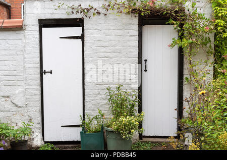 Un vieux hangar en briques avec deux portes peintes en noir et blanc Banque D'Images