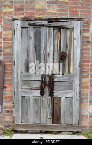 Meubles anciens en bois patiné avec heurtoir de porte rouillée et poignées rouillées comme vu sur Vieux rustique mur de briques. Banque D'Images