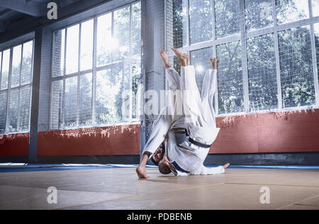 Deux combattants judo montrant des compétences techniques, tout en pratiquant les arts martiaux dans un fight club. Mettre en place les deux hommes en uniforme. lutte, karaté, de la formation, de l'art, l'athlète, la concurrence concept Banque D'Images