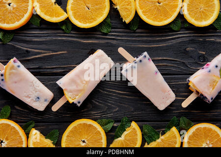 Vue de dessus les popsicles maison gastronomique avec des tranches d'orange et menthe sur surface en bois Banque D'Images