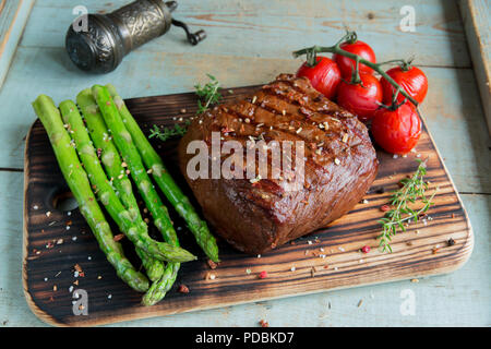 Pavé de boeuf grillée aux épices tomates asperges sur une surface en bois Banque D'Images