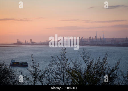 À la recherche sur l'estuaire de la Seine à partir de la Côte de Grâce au-dessus de Honfleur au coucher du soleil avec les grues du port à conteneurs du Havre dans la distance Banque D'Images