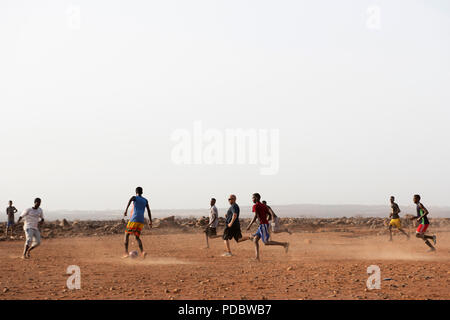 Service des membres affectés à la Force opérationnelle interarmées - Corne de l'Afrique participent à un match amical de football avec les enfants du village voisin, à l'extérieur du village de Chebelley, Djibouti, 3 août 2018. Plus de 30 soldats et aviateurs canadiens se sont portés volontaires pour l'activité de sensibilisation organisée par le 404e Bataillon des affaires civiles. (U.S. Air National Guard photo par le Sgt. Sarah Mattison) Banque D'Images