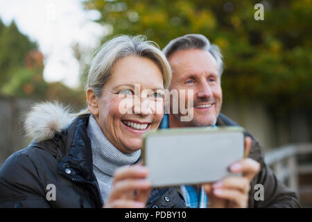 Mature couple using camera phone Banque D'Images