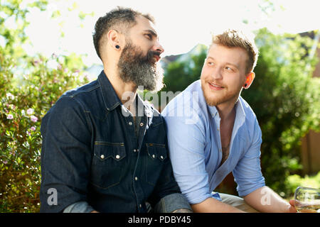 Homme gay couple talking in garden Banque D'Images