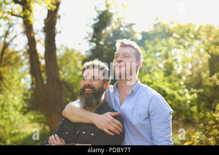 Homme affectueux gay couple hugging in sunny park Banque D'Images