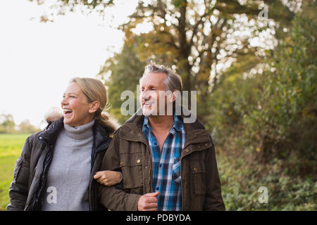 Mature couple walking arm in arm in autumn park Banque D'Images