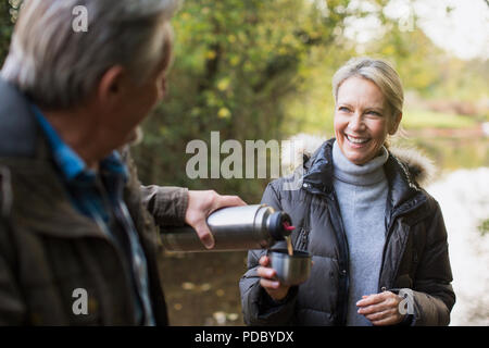 Happy mature couple drinking coffee de verre isolé contenant dans autumn park Banque D'Images