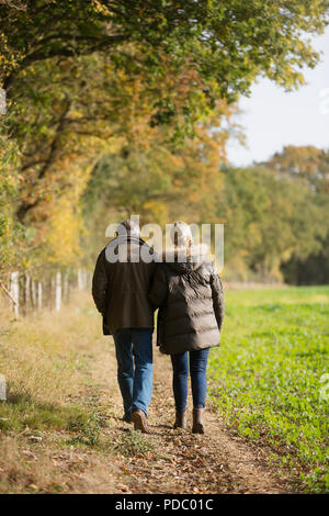 Affectueux mature couple walking in rural field automne ensoleillé, Banque D'Images