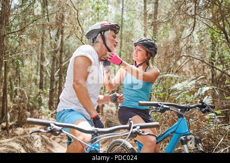 Fille aidant père avec casque vtt sur le sentier dans les bois Banque D'Images