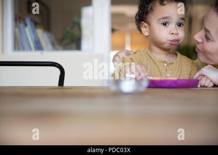 Mère regardant mignon, innocent boy eating at table Banque D'Images