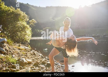 Playful couple à sunny summer lake Banque D'Images