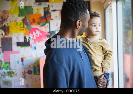 Père holding curieux, fils innocent baby looking out window Banque D'Images