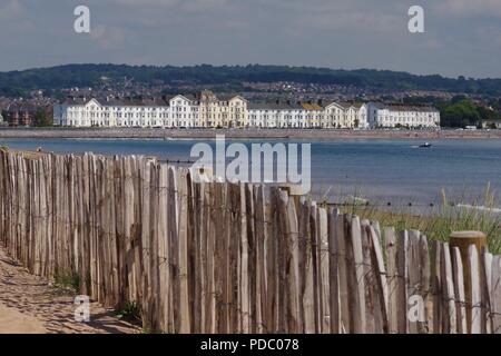 Propriété le long du front de mer d'Exmouth période Strand, vu de Dawlish Warren on étés un jour. La stabilisation des dunes de sable clôture en premier plan. Devon, Royaume-Uni. Banque D'Images