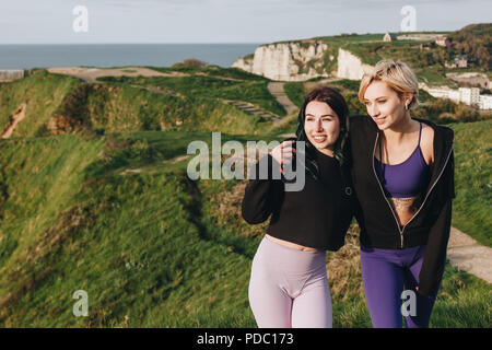 Happy in sportswear élégant hugging on cliff, Etretat, Normandie, France Banque D'Images