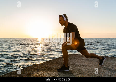 Athletic man casque en faisant un tailleur s'accroupit au cours de la formation sur mer Banque D'Images