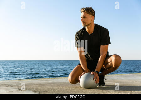 Beau sportif adultes assis avec fit ball sur le littoral et à l'écart Banque D'Images