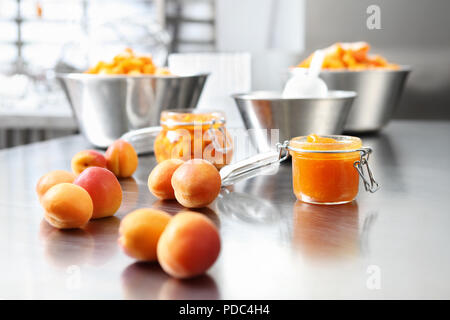 À partir de la confiture d'abricots dans un bocal de verre sur une surface en acier inoxydable poli en pâtisserie plan Banque D'Images