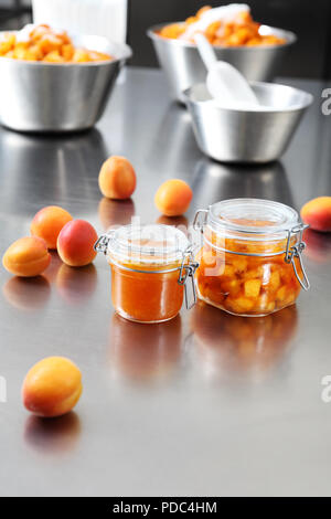 À partir de la confiture d'abricots dans un bocal de verre sur une surface en acier inoxydable poli en pâtisserie plan Banque D'Images