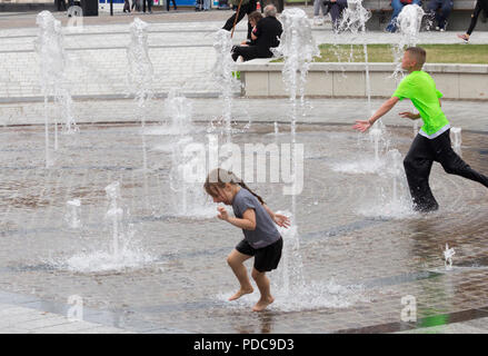 Stockton on Tees, Angleterre du Nord-Est. United Kingdom. 8 Août, 2018. Météo France : undetered par le ciel couvert et un temps plus frais, les enfants jouent dans la rue Fontaine dans Stockton on Tees, Angleterre du Nord-Est. De fortes pluies, qui seront accueillis par les agriculteurs et jardiniers, est prévue pour de nombreuses régions du Royaume-Uni à la fin de semaine Crédit : ALAN DAWSON/Alamy Live News Banque D'Images